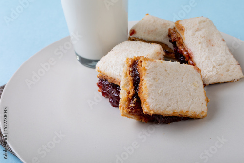 Close-up of peanut butter and jelly sandwich slices served with milk glass in plate on table