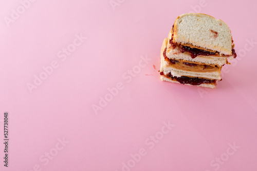 High angle view of stacked peanut butter and jelly sandwiches on pink background with copy space