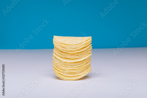 Close-up of stacked potato chips on table against blue background with copy space