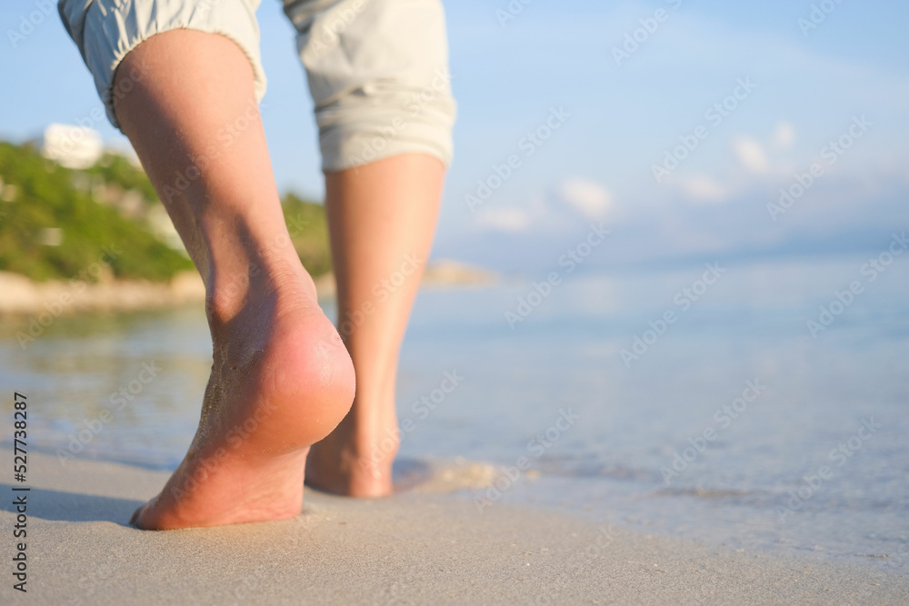 woman walking to sea and beach on a beautiful island Ocean foam wrapped around a girl's leg. Her legs touched the splashing water. Hit the skin on the legs and she walked in the soft sunshine morning woman walking to sea and beach on a beautiful island Ocean foam wrapped around a girl's leg. Her legs touched the splashing water. Hit the skin on the legs and she walked in the soft sunshine morning