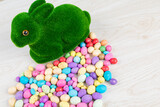 High angle view of artificial moss bunny with colorful candy easter eggs on table