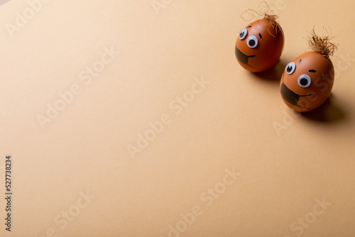 High angle view of easter eggs with face mask drawing and strings on top against orange background
