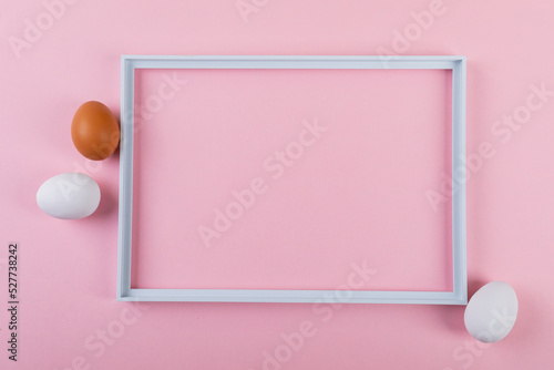 Directly above shot of easter eggs by empty frame on pink background with copy space