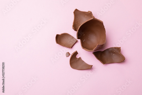 Close-up of broken chocolate easter eggs on pink background with copy space