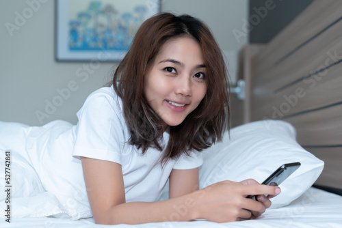 Young woman using smartphone on bed