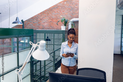 African american young businesswoman using digital tablet while standing in modern office photo