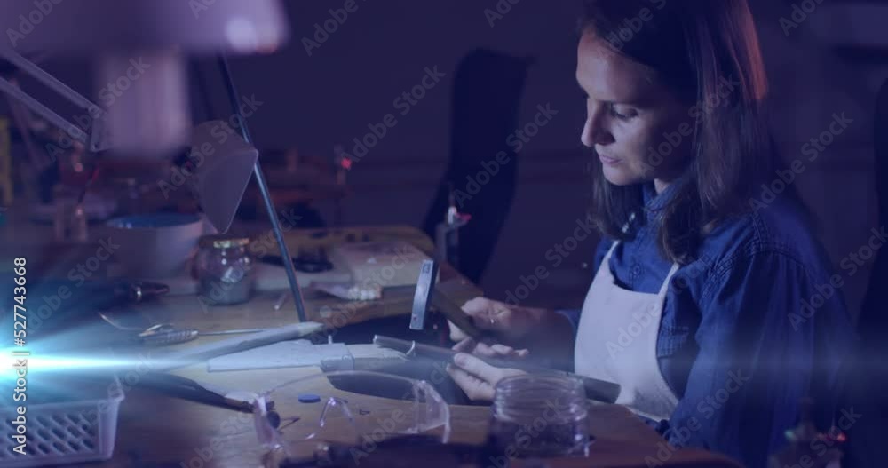 Animation of glowing light over caucasian woman using tools working in workshop Animation of glowing light over caucasian woman using tools working in workshop