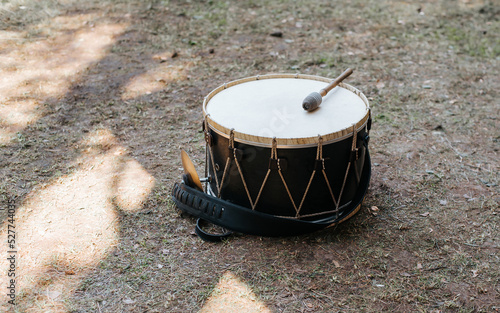 Medieval drum with drumstick lying on grass outdoors