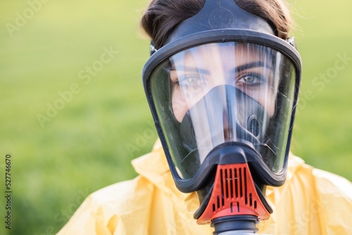Person in overalls and gas mask call to save the planet while standing on green field on sunset. Concept of bad ecology and environmental protection