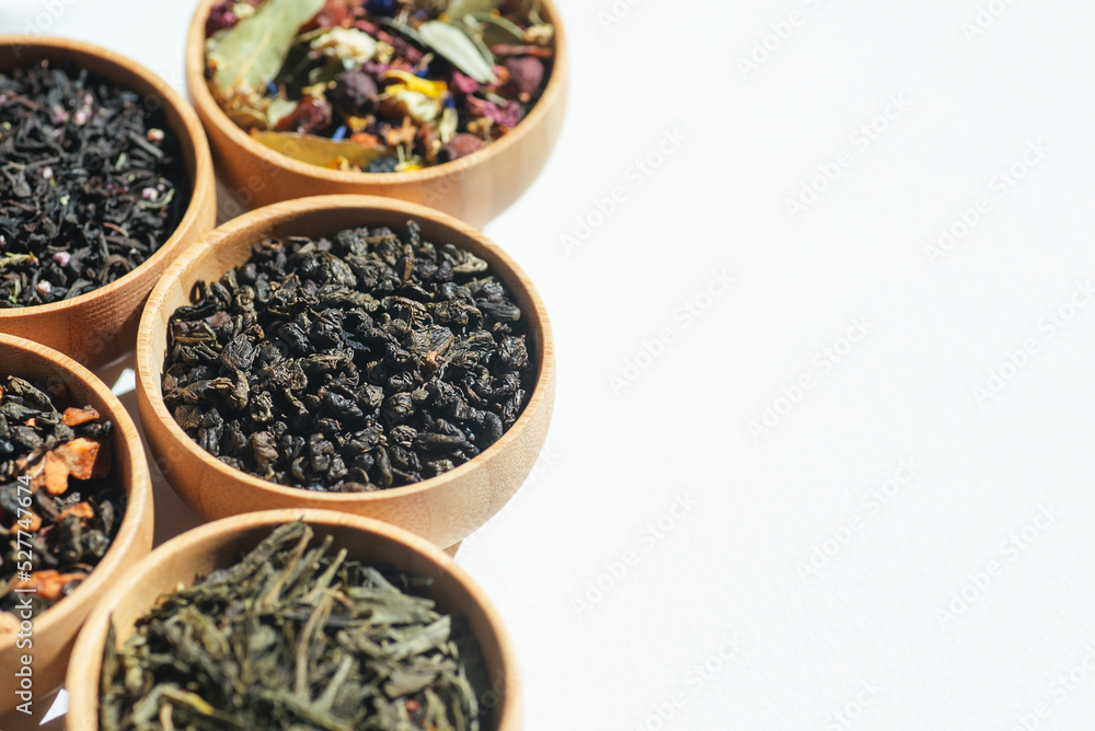 Different types of green, black and herbal tea in a wooden bowl. Variety of dry leaves and flowers. Organic high-quality ingredients for a drink