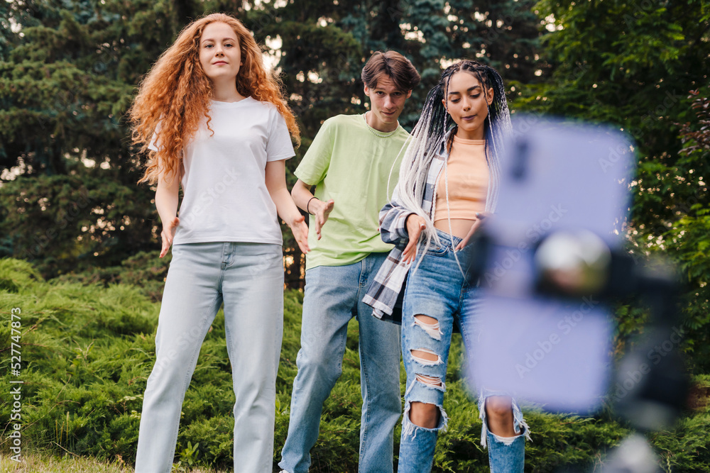 Group of students or teenagers looking at smartphone screen, recording video that are trending, starting live stream, smiling. Young students having fun Group of students or teenagers looking at smartphone screen, recording video that are trending, starting live stream, smiling. Young students having fun