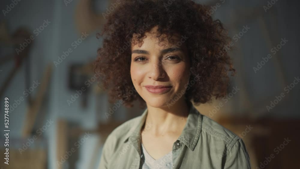 Portrait of a Beautiful Female Artist with Curly Hair Looking at Camera, Smiling and Feeling Happy. Young Successful Multiethnic Arab Woman Working in Carpentry Workshop. Portrait of a Beautiful Female Artist with Curly Hair Looking at Camera, Smiling and Feeling Happy. Young Successful Multiethnic Arab Woman Working in Carpentry Workshop.