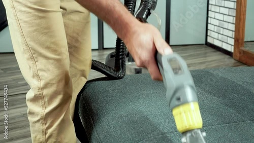Close up shot of Caucasian person hands in yellow gloves using special vacuum cleaner equipment vacuuming sofa in room, cleaning furniture, clean up house, domestic work concept. High quality footage
