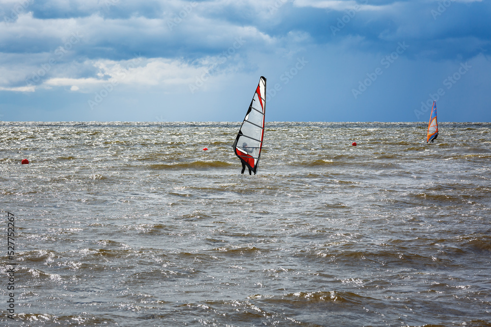 Naklejka premium Windsurfing.Windsurfers have fun on the water against a stormy sky.