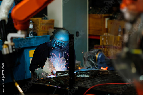 Welder is working to welding and grinding at his workplace in the workshop, while the sparks fly all around him.