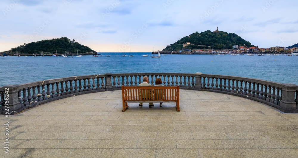A couple on la Concha promenade bench with a view the bay in San Sebastian Spain