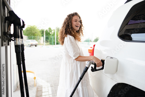 Bilde på lerret Young curly woman refueling car at gas station