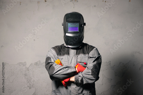 Serious welder man standing in the welding helmet on gray background. photo