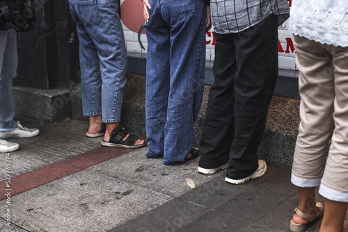 Close-up legs of people waiting in queue outside the store.