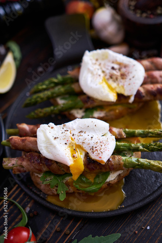 Tasty breakfast - toasts with cream cheese, poached eggs and Asparagus wrapped with bacon and spices on a plate