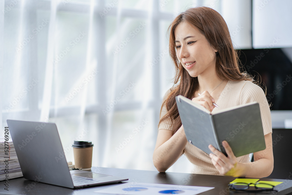 Asian woman working at home on laptop computer manages her business at work. Document planning, calculator, analyze financial reports. business plan investment Asian woman working at home on laptop computer manages her business at work. Document planning, calculator, analyze financial reports. business plan investment