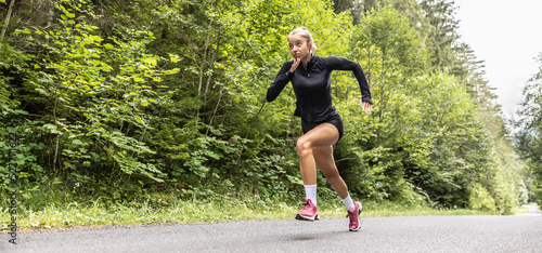 Fototapeta Naklejka Na Ścianę i Meble -  Dedicated sprinter runs on an asphalt road outdoors training for better performance
