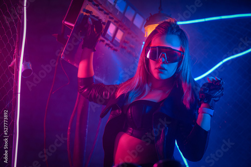 Young girl in the leather jacket is posing in neon lights.