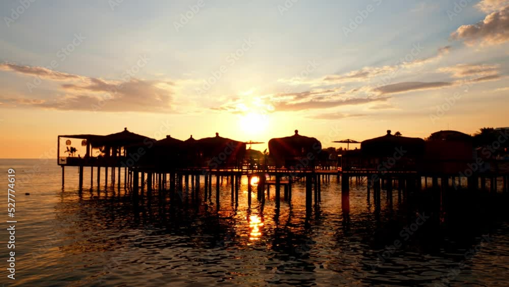 Water villas above sea. Sunbeds and houses above water at sunset in sunlight. Nature landscape. Luxury beach resort. Evening on tropical island. Summer weekend rest. Paradise on earth. Dream life. Water villas above sea. Sunbeds and houses above water at sunset in sunlight. Nature landscape. Luxury beach resort. Evening on tropical island. Summer weekend rest. Paradise on earth. Dream life.