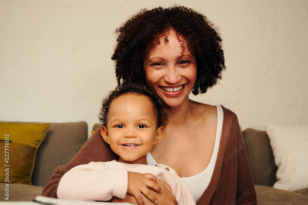 Happy biracial mother and daughter smiling and looking at camera in living room at home Happy biracial mother and daughter smiling and looking at camera in living room at home