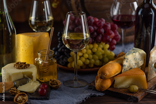 Cheese and wine tasting still life. Glass of wine, bottle of wine, grape. Nuts, honey, dipper. Empty copy space, mock up