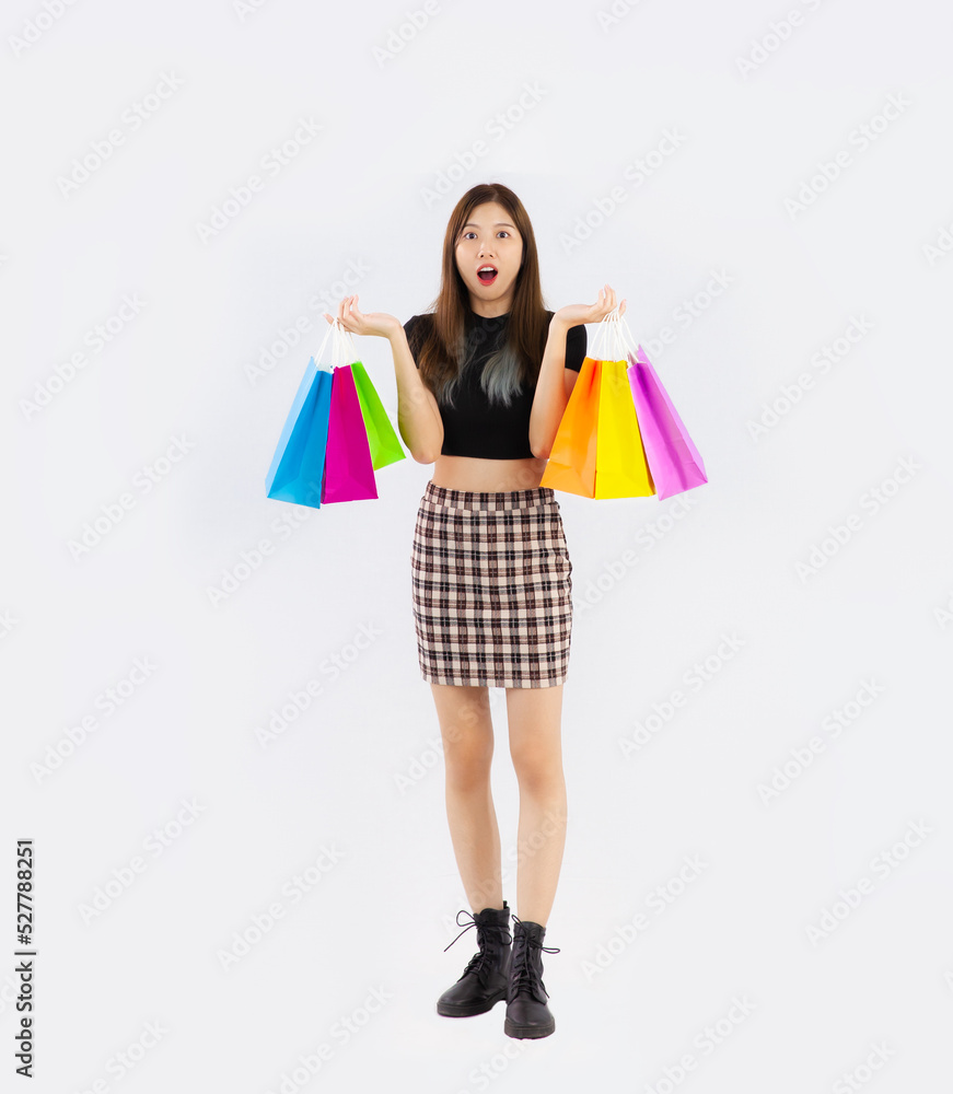 Young asian woman in black crop shirt carrying the colorful shopping bags posing wow on the white background full body.