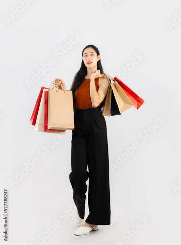 Pretty asian woman long hair carrying and holding red and brown paper shopping posing walking with full body on white background.