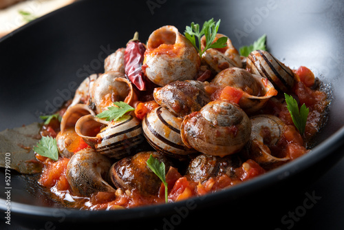 Piatto di deliziose lumache cotte e condite con sugo piccante, cibo italiano  photo