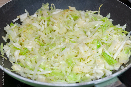 Appetizing fried cabbage in an old frying pan on an old wooden background close-up.