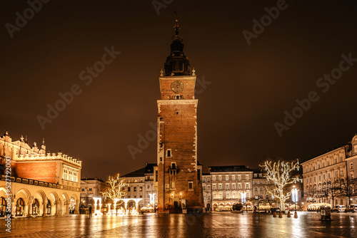 Krakow after rain,Poland.Main square with famous Christmas markets,Rynek Glowny at night with reflection,decorated timber huts,Xmas tree.Festive atmosphere,blurred people in motion,illuminated city © Eva