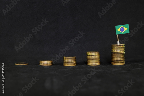 Obraz na płótnie Brazil economic growth, recovery after financial crisis and peso appreciation concept. Brazilian flag in increasing stack of coins in dark black background. w salonie