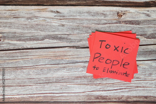 List of toxic people to eliminate concept. Red sticky note in wooden background with copy space.