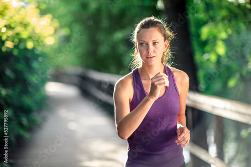 Young focused healthy woman running in nature