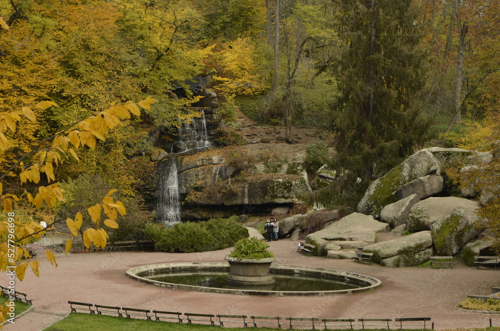 Obraz premium Beautiful autumn park with rocks, pond and cave.