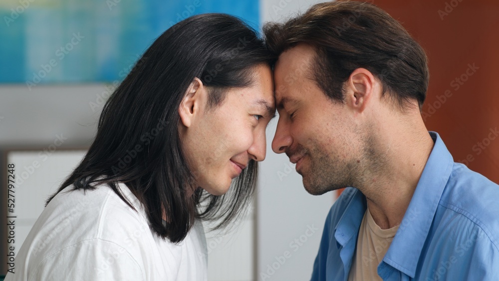 Closeup of diverse gay couple touching foreheads and look into each other eyes Closeup of diverse gay couple touching foreheads and look into each other eyes