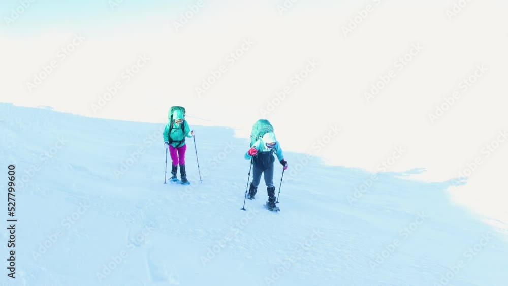 Two women walk in snowshoes in the snow, winter trekking, two people in the mountains in winter, hiking equipment Two women walk in snowshoes in the snow, winter trekking, two people in the mountains in winter, hiking equipment