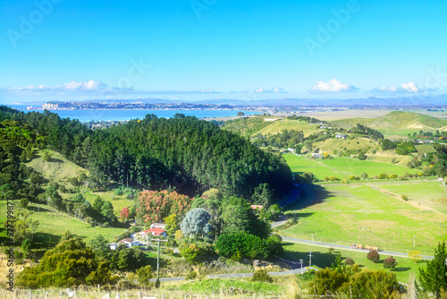 View from a high vantage point over farmhouse amongst lush meadows and green hills. Beautiful autumn day at a seaside region of Hawkes Bay  New Zealand