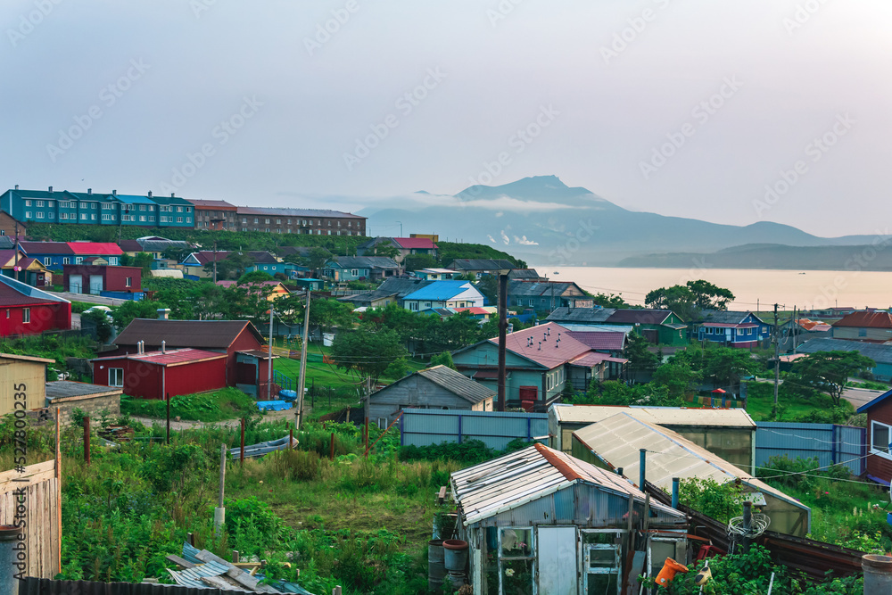 landscape of the town of Yuzhno-Kurilsk on the island of Kunashir with a view of the sea bay and the Mendeleev volcano in the distance