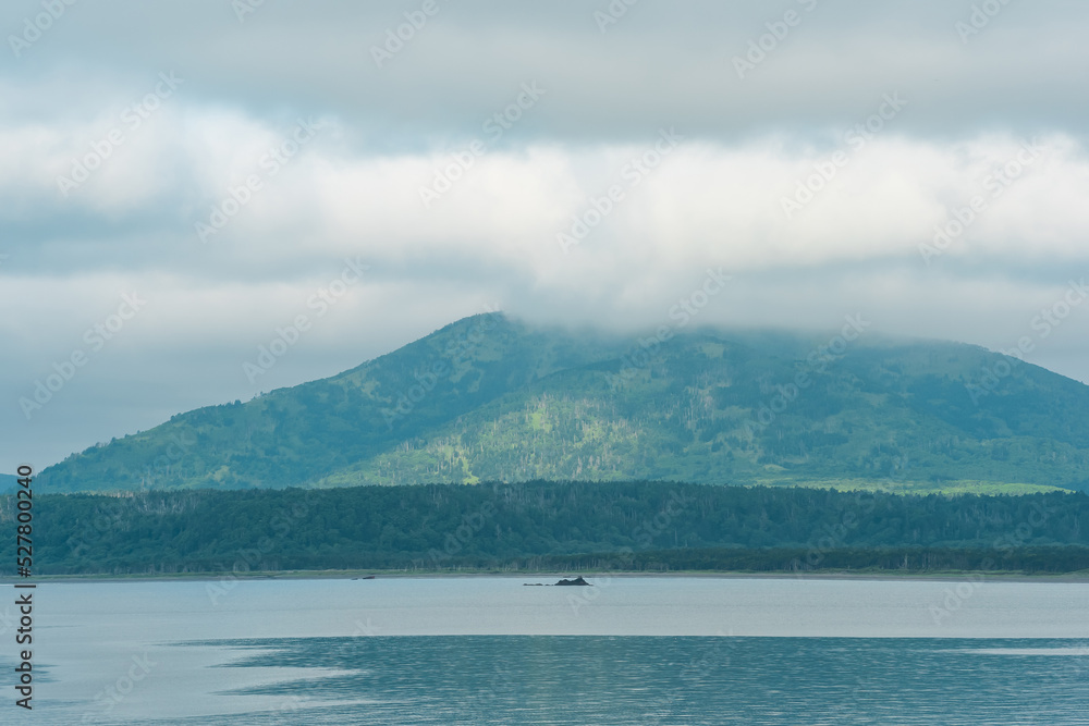 sea bay with foggy mountains in the background, view of the Mendeleev volcano on a cloudy day