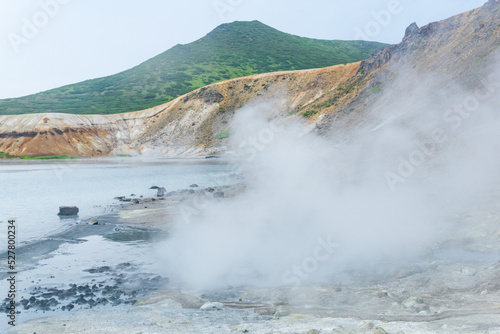 boiling and steaming hydrothermal outlet on the shore of the hot lake in the caldera of the Golovnin volcano on the island of Kunashir