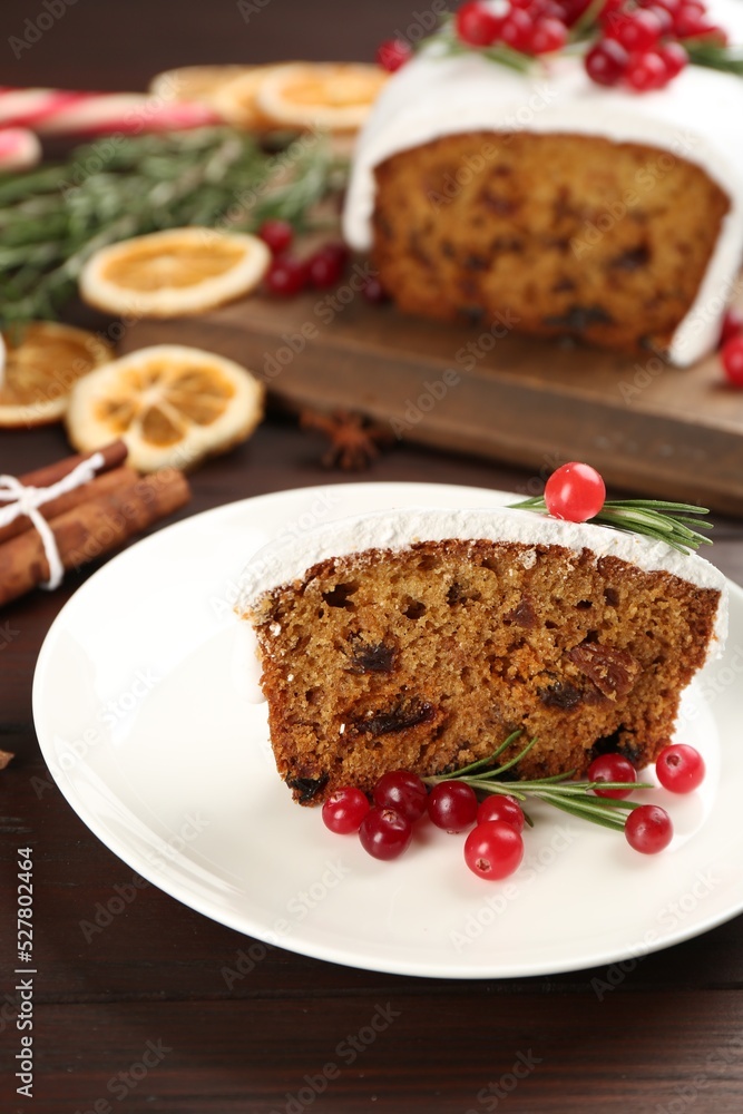 Traditional classic Christmas cake decorated with cranberries and rosemary on wooden table