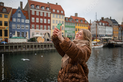 A tourist takes a selfie while in Nyhavn canal in the Danish capital, Denmark tourism concept.