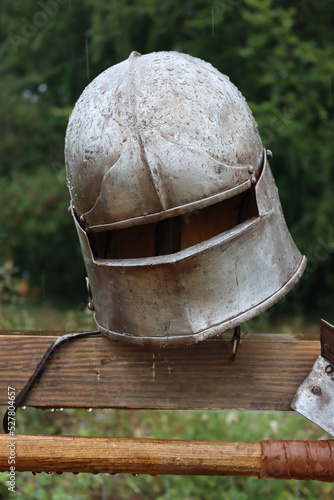 A medieval sallet type helmet on a wooden post in the rain