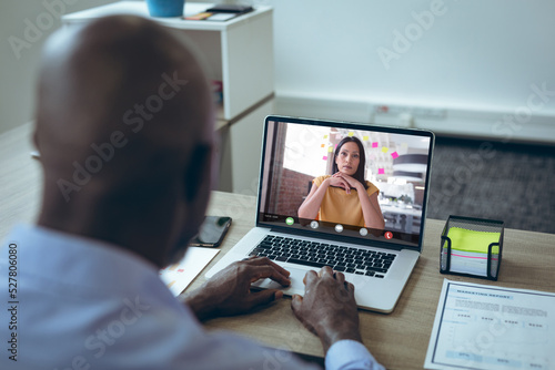 African american businessman brainstorming with female colleague during video call on laptop