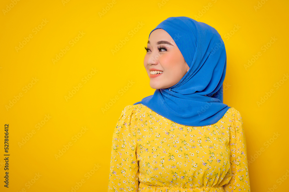 Cheerful young Asian woman in casual dress looking away at copy space isolated on yellow background Cheerful young Asian woman in casual dress looking away at copy space isolated on yellow background